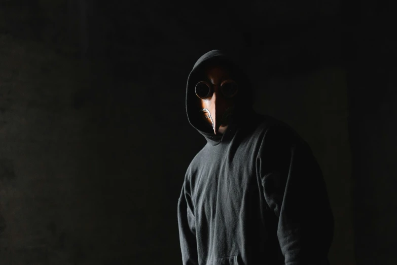 a man wearing a black hoodie standing in the dark