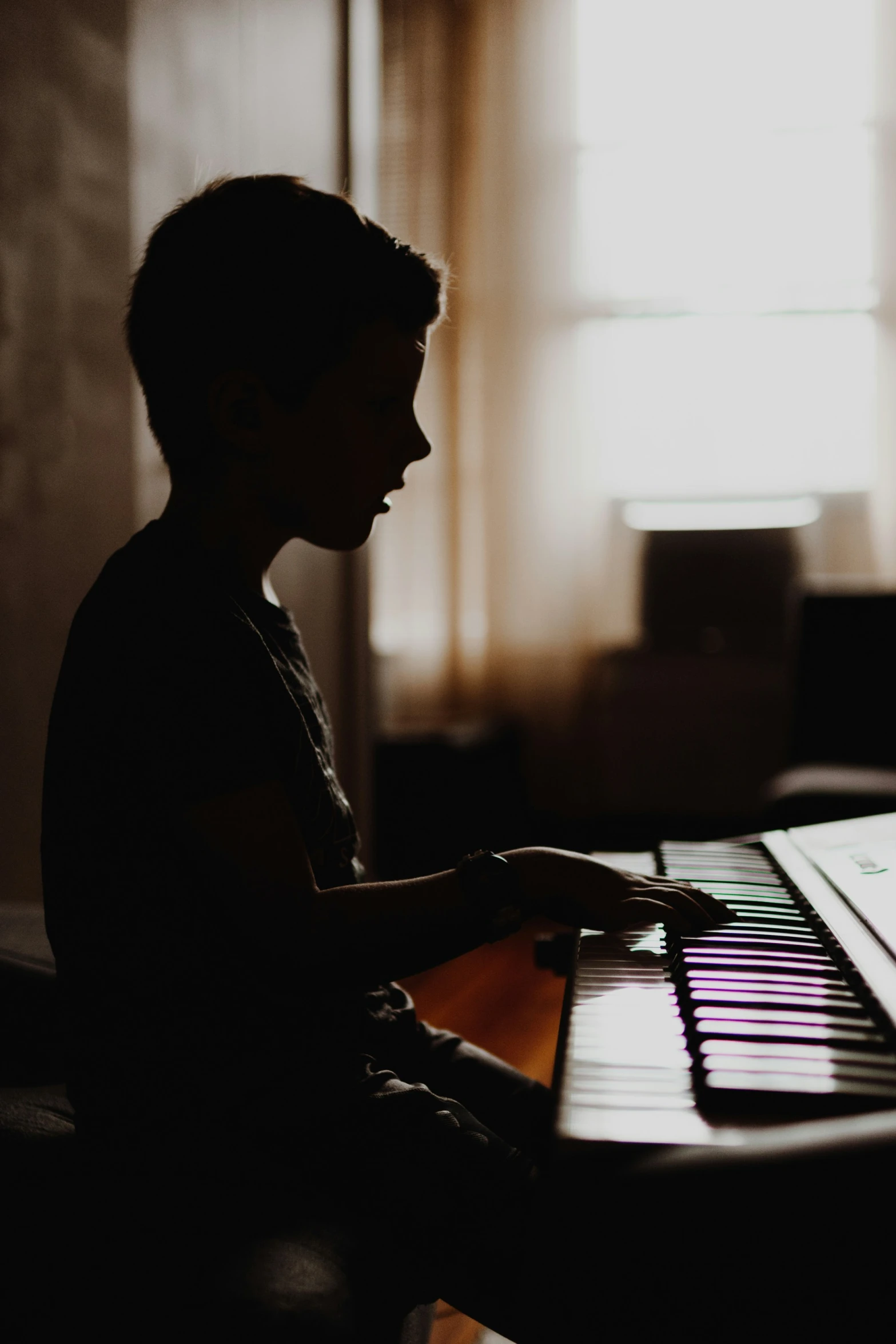 the boy is sitting and playing the piano