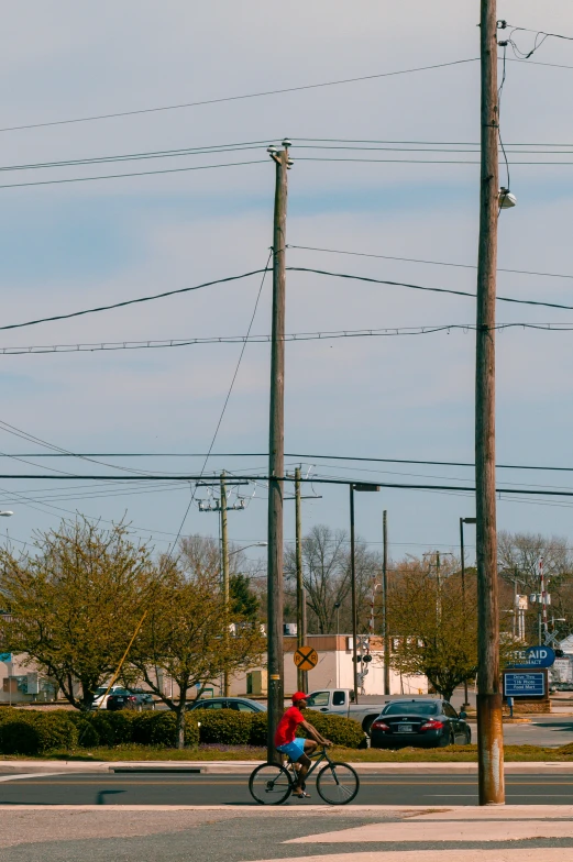 a man rides his bike down the street near power lines