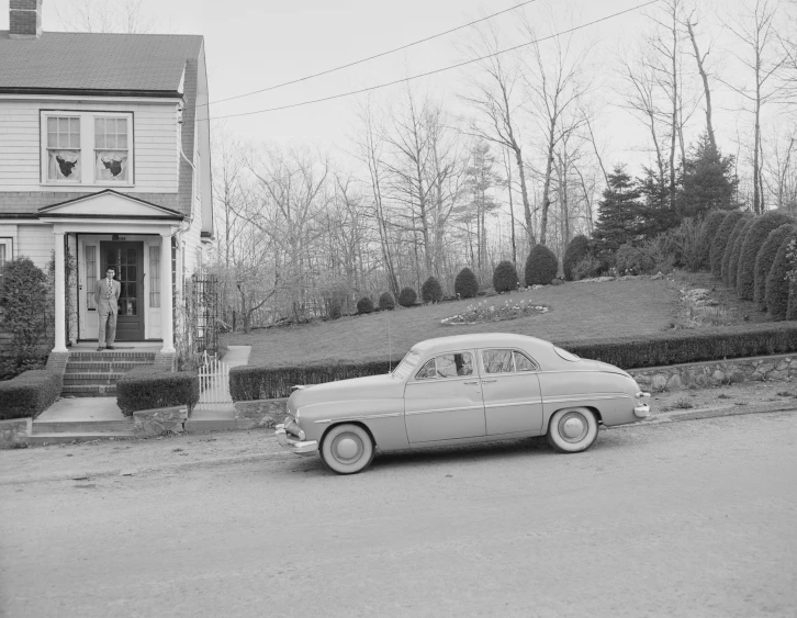 a classic car is parked next to a house