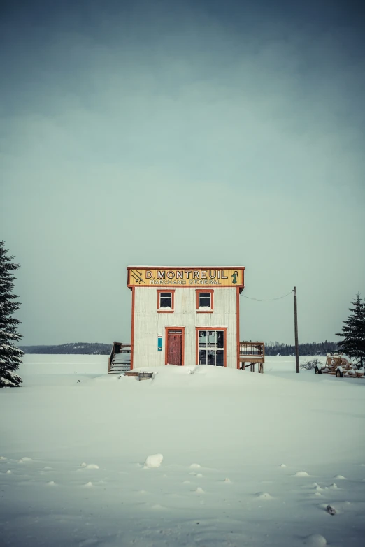 a small red and yellow building surrounded by snow