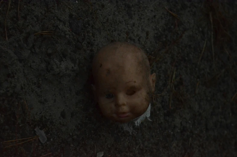 a worn doll lying in the dirt with eyes