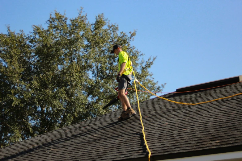 a man on a roof, climbing a wire with his hand