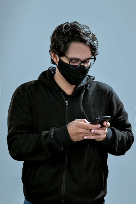 a person wearing a mask while looking at his cell phone
