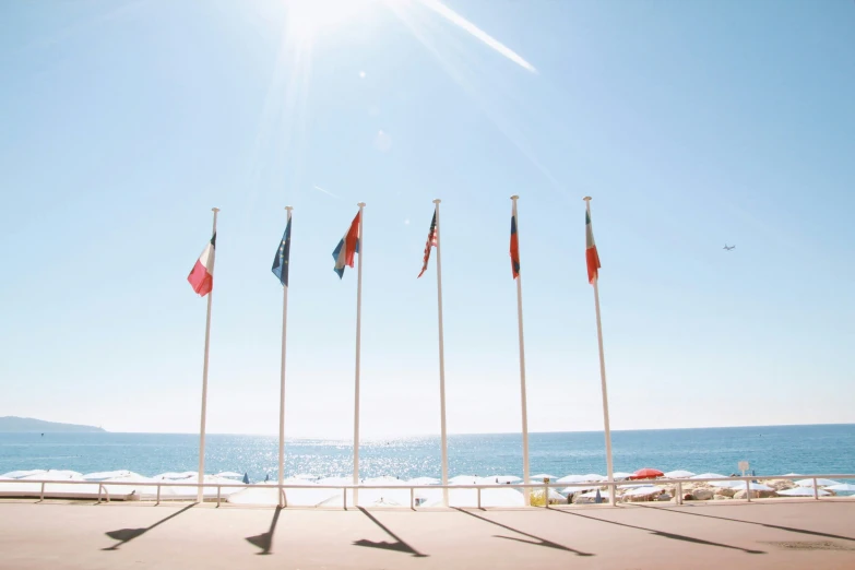 several flags are flying next to the water