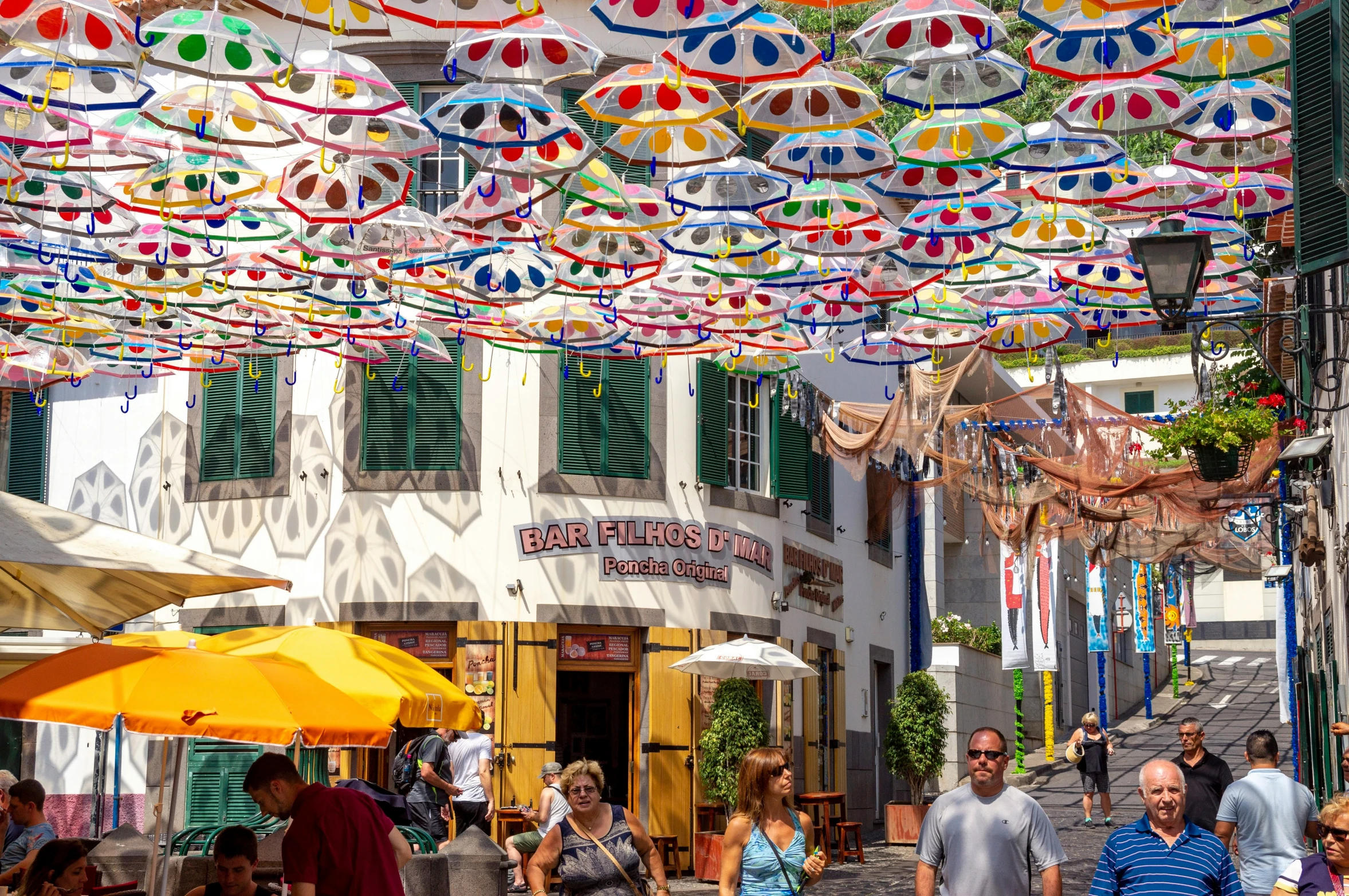 this shop front area has a variety of umbrellas hanging above it