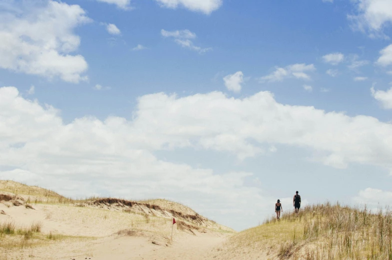 a couple of people standing on top of a sand dune