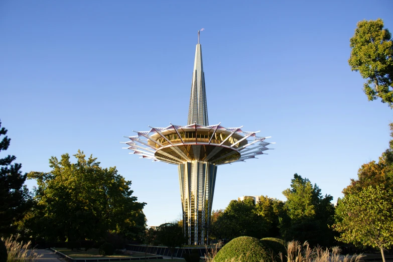 a statue of a tall, pointed spire with a garden in front of it