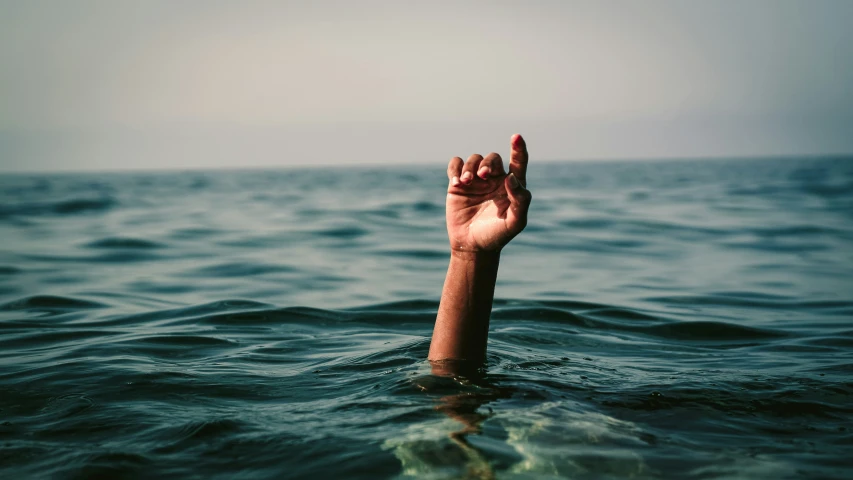 a hand rising up into the air above water