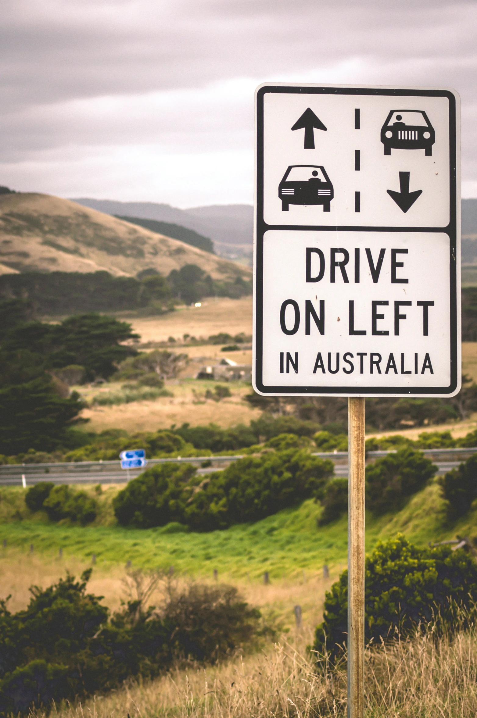 there is a sign that is telling drivers to drive on left and an overhang in the background