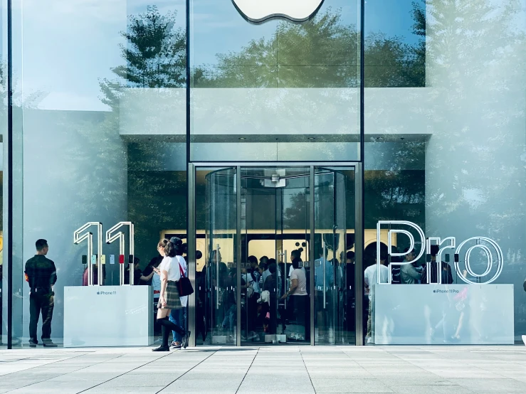 a group of people standing in front of a apple store