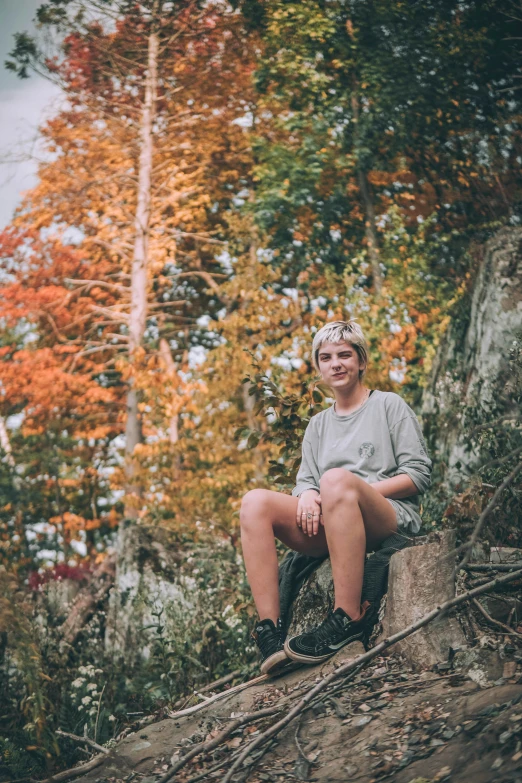 a smiling lady sitting on a tree stump