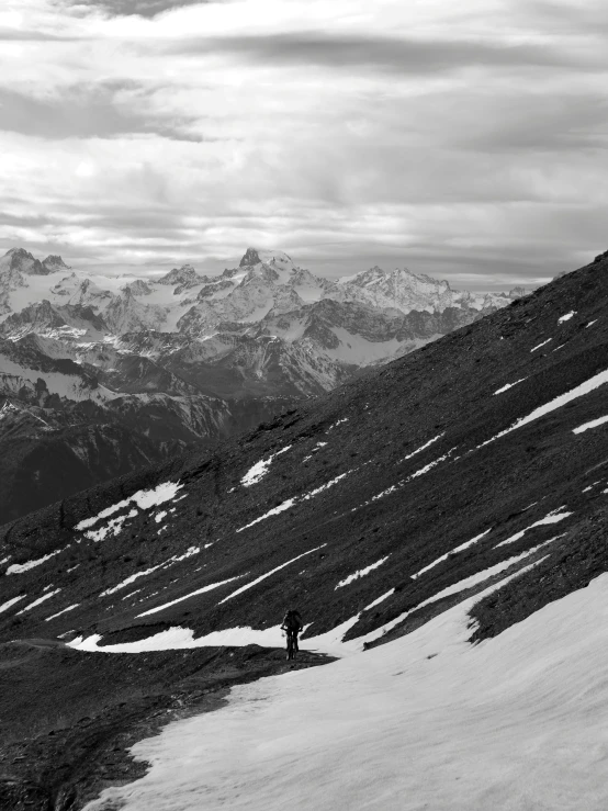 black and white pograph of skier standing on the summit of snowy hill