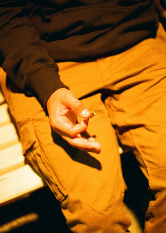 someone sitting on top of a bench holding a cigarette