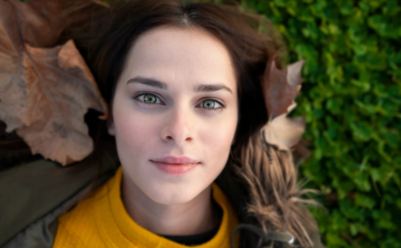 a girl laying with leaves on her head