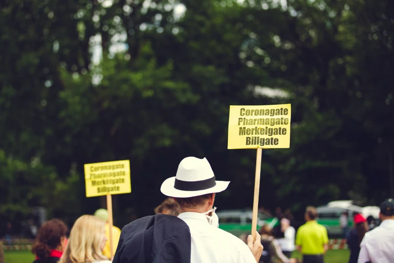 a man in a hat holds up signs