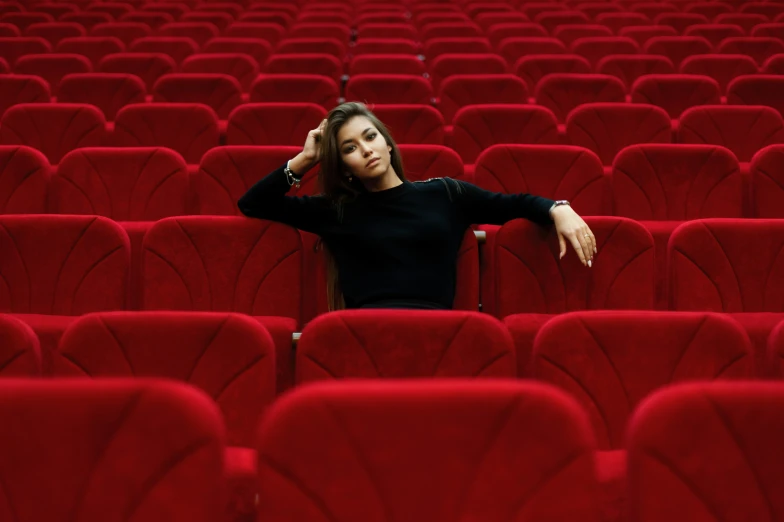 a girl sitting on the middle of a row of seats