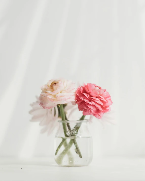 an open glass vase with three flowers in it