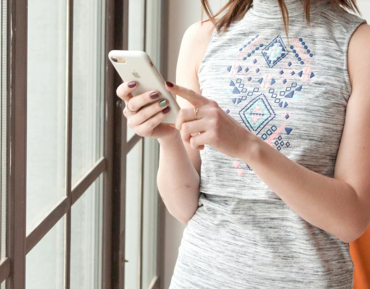 a woman with red lips wearing grey shirt looking at a cell phone