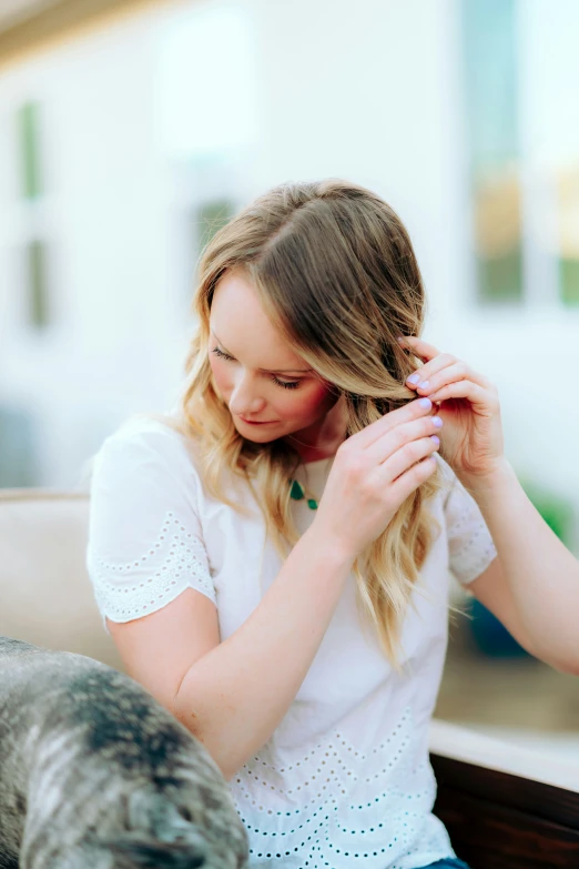 a woman is getting her hair dried while sitting on a sofa