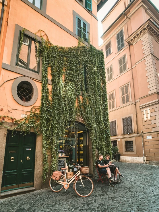 two people sitting in front of a building covered with ivy