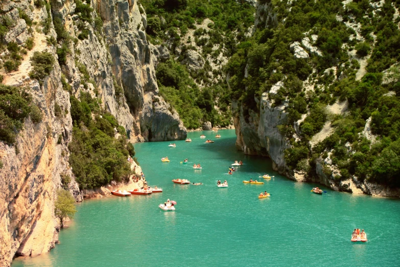 a river filled with people in boats and boats near cliffs