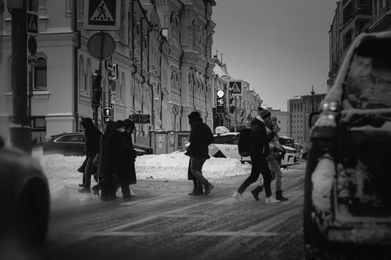 people walking down a snowy sidewalk in a city