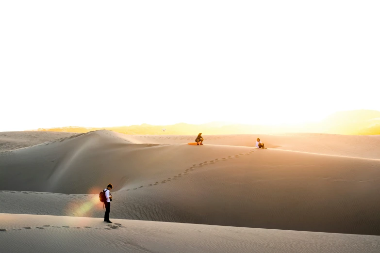 people on sand dunes at sunrise in the desert