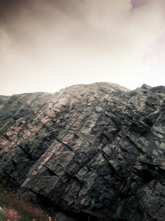 the mountainside with rocks and grass growing on the slope