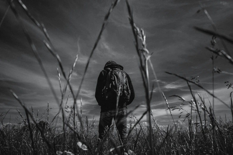 a man walking through a field with tall grass