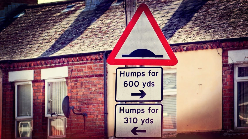 three street signs in front of a brick building