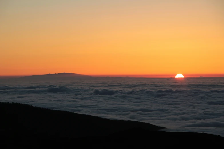 the sun is rising over some low mountains