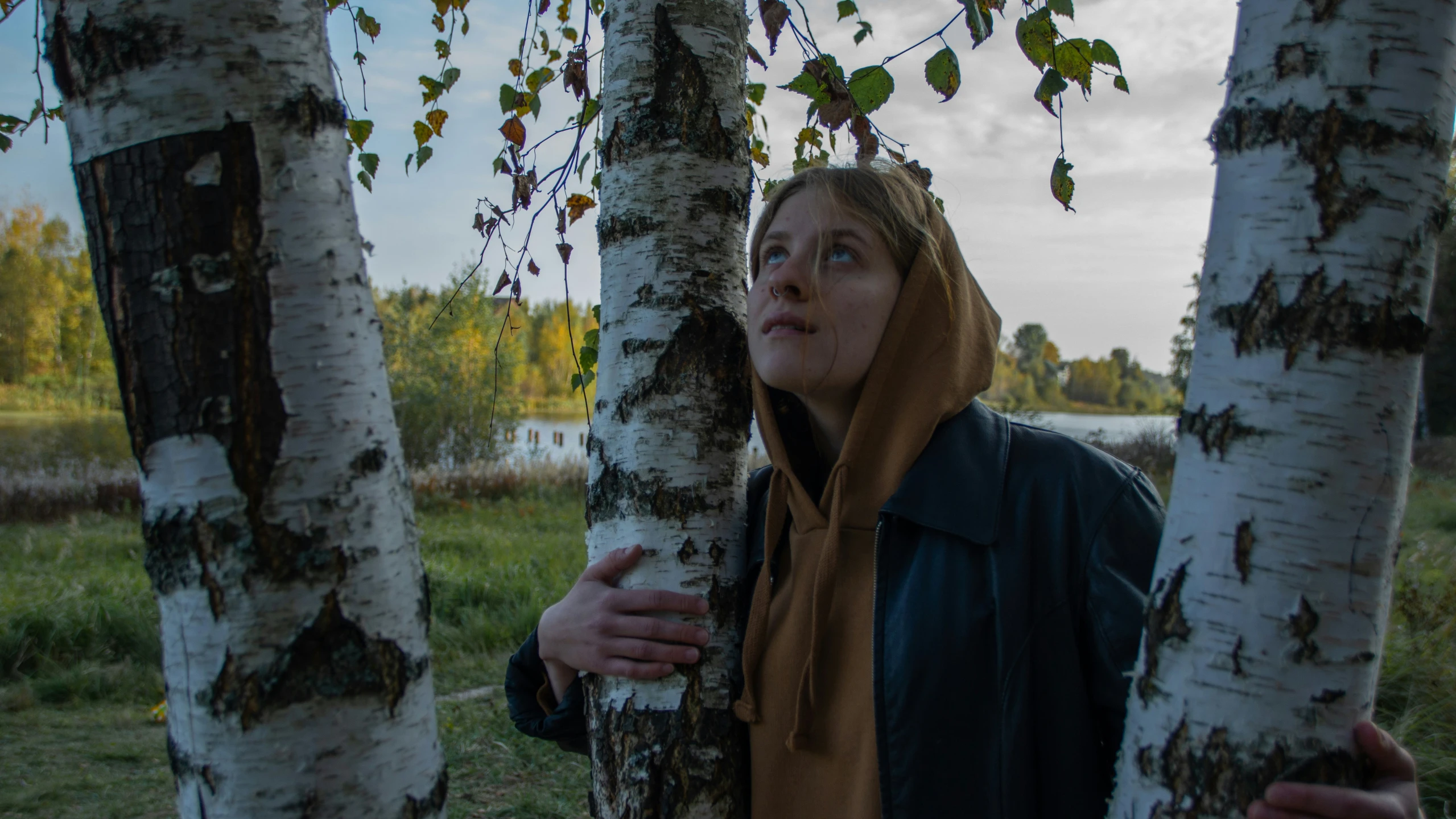 a woman hiding behind some tree trunks