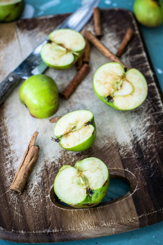 sliced apples on a  board with some cinnamon sticks