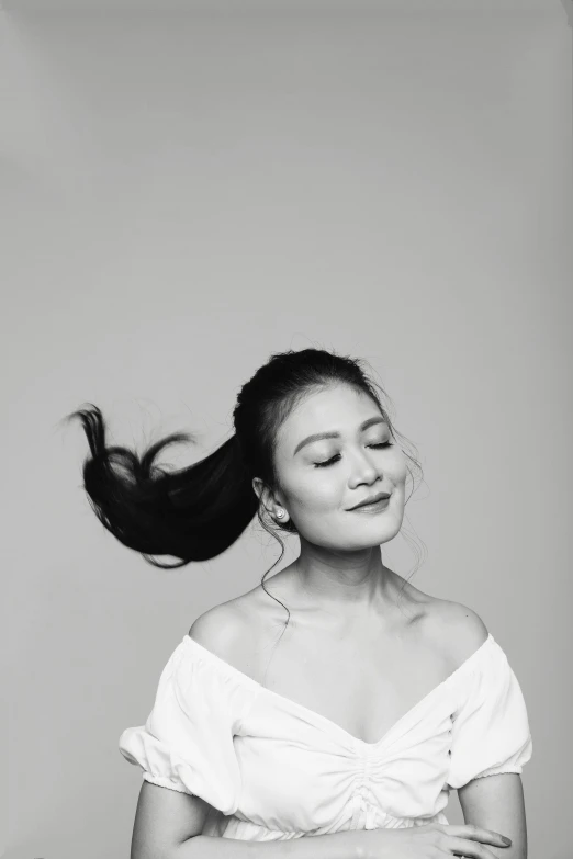 a woman wearing a top and holding her hair in the wind