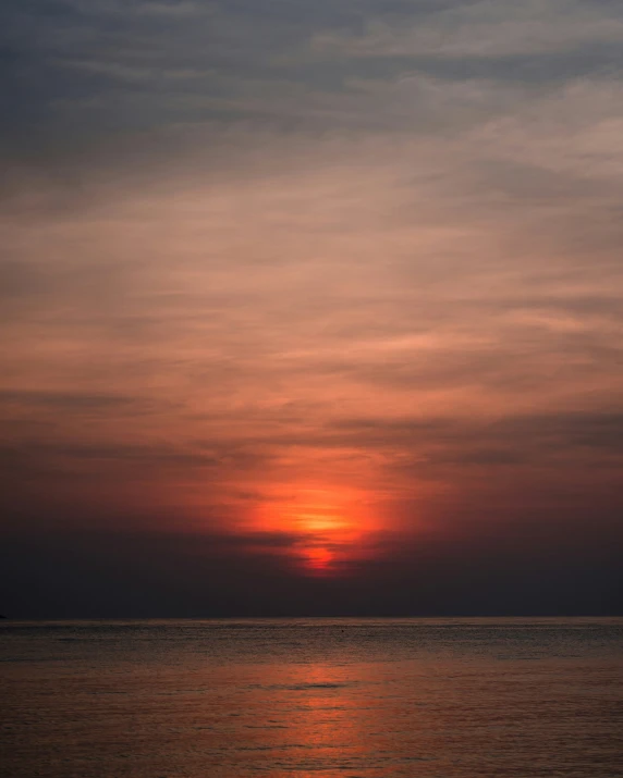 the setting sun is seen through the clouds above a body of water