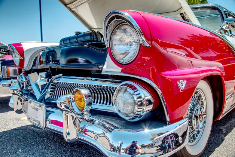 an old red and chrome car in the parking lot