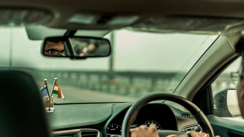 man is driving a car while holding a small flag