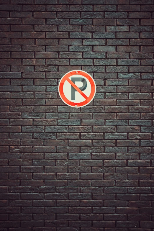 a no parking sign on a dark brick wall