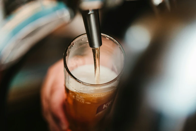 a person pouring beer into a glass filled with it