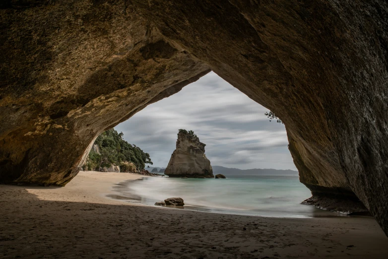 an opening in a rock formation on a sandy beach