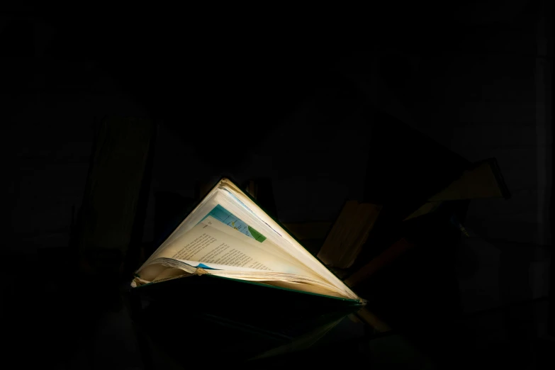 an open book is sitting on a table with black background