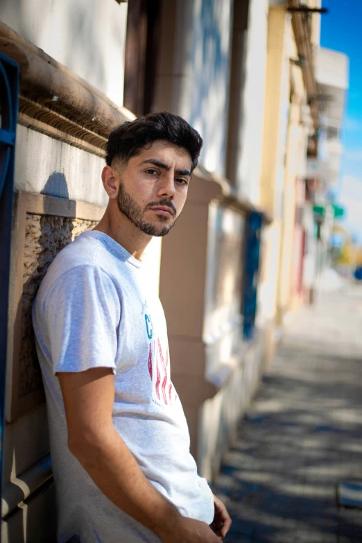 a man leans against a wall with his eyes shut