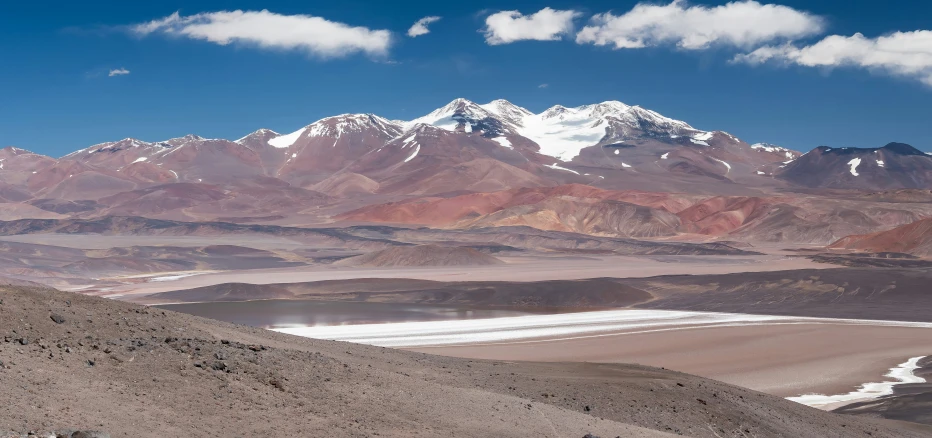 the view from a mountain in the distance with snow covered mountains