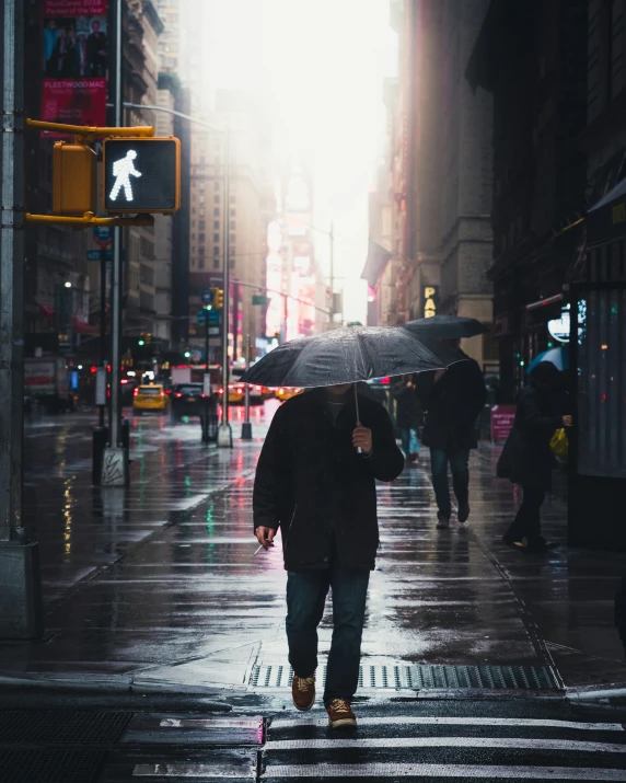 people walking across the street with umbrellas on a rainy day