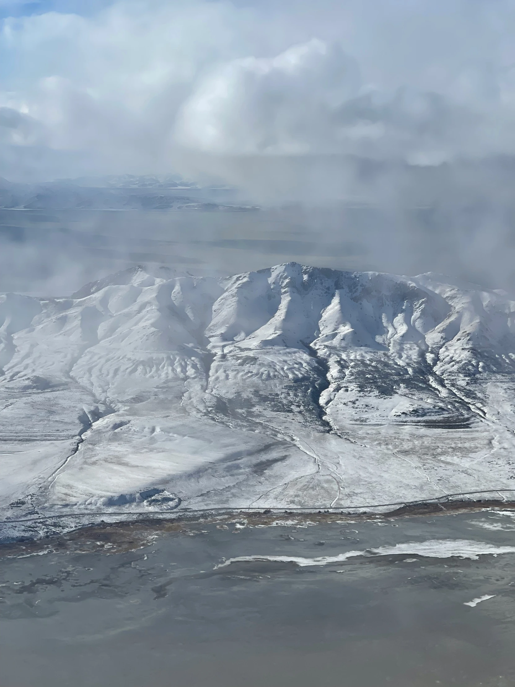 a snow covered mountain is seen under the cloudy sky