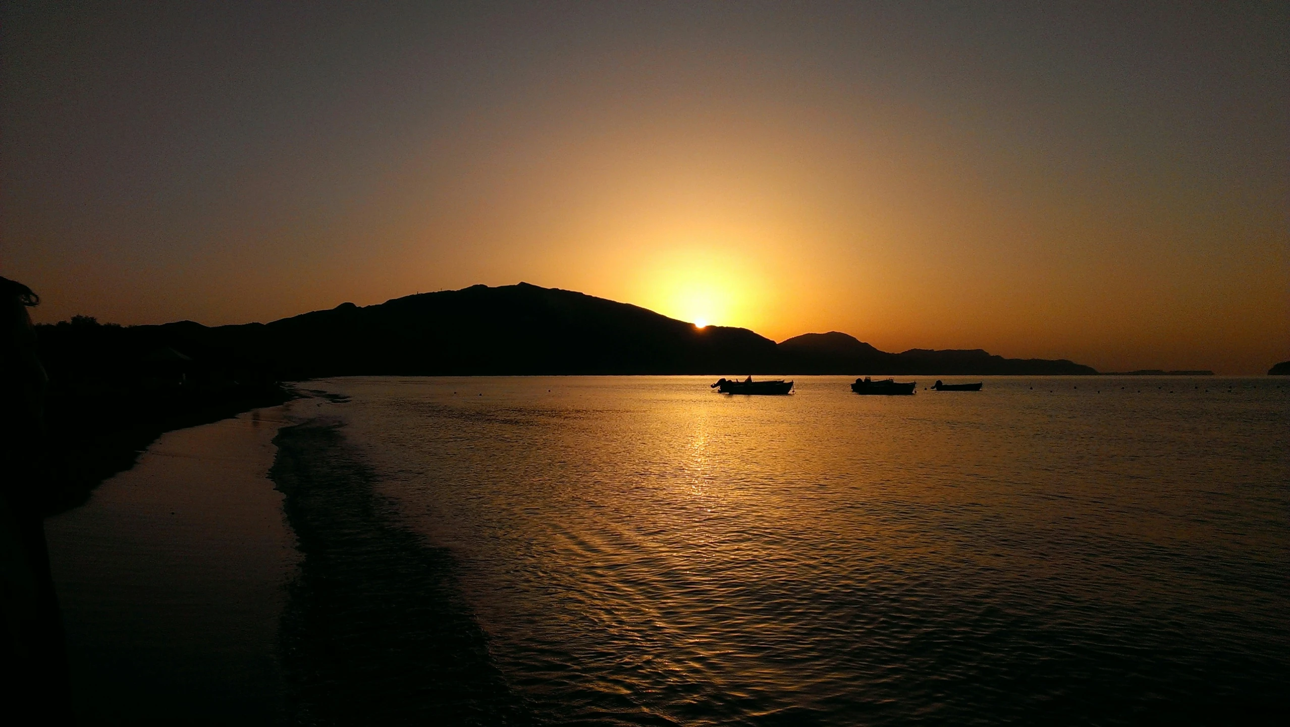 boats floating on the water and a sunset behind them