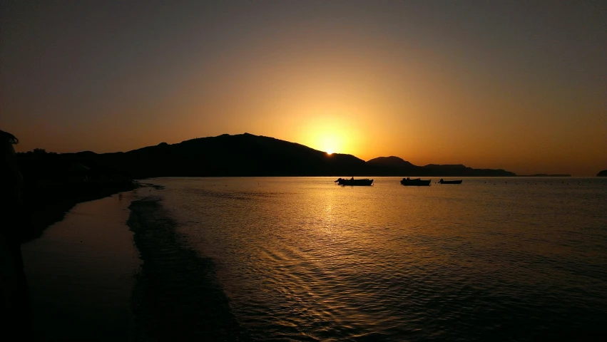 boats floating on the water and a sunset behind them