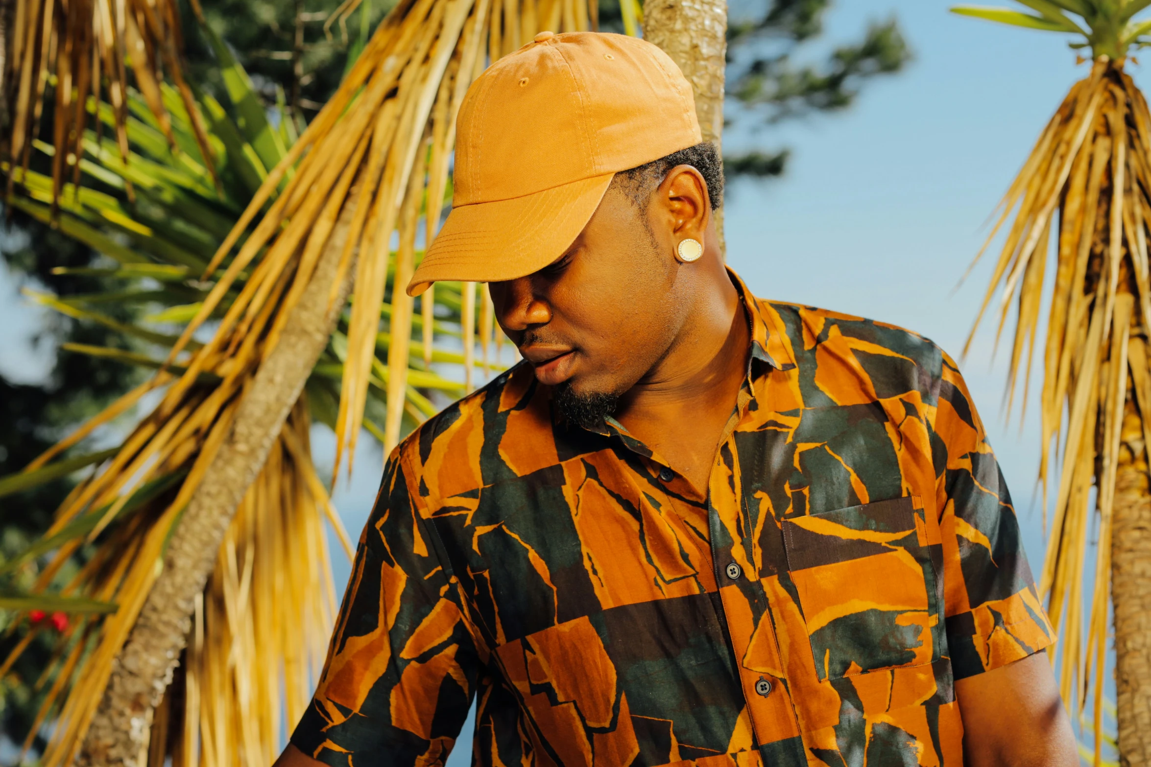 a man in a patterned orange shirt wearing a yellow hat