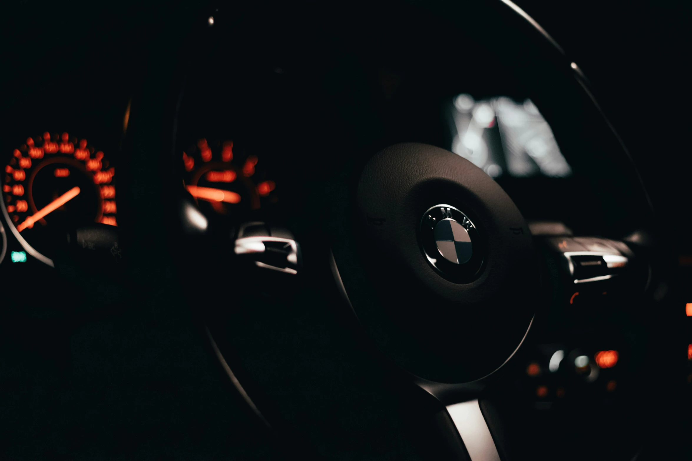 steering wheel of car illuminated in dark with dashboard lights